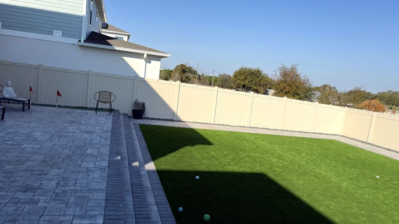 Backyard in daylight with paver walkway and turf lawn